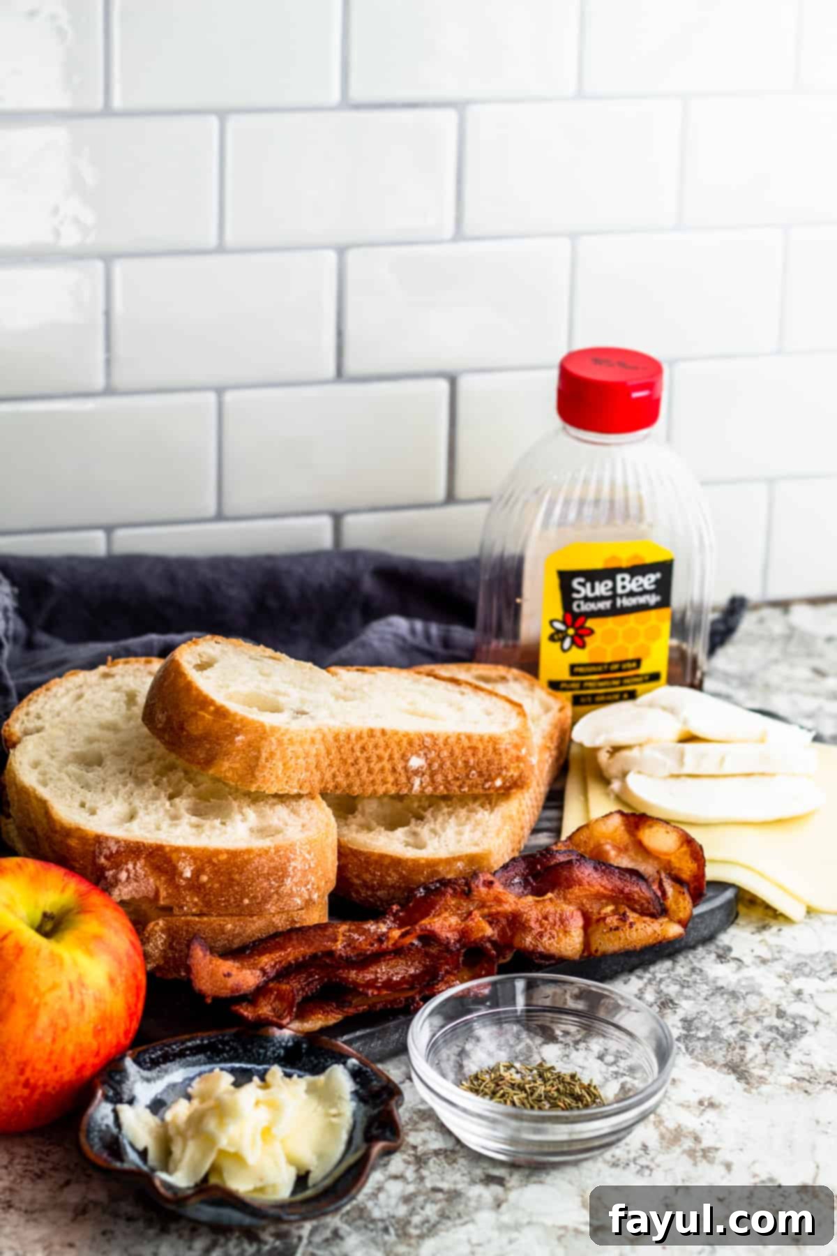 Ingredients for bacon and apple sandwich laid out on white counter.