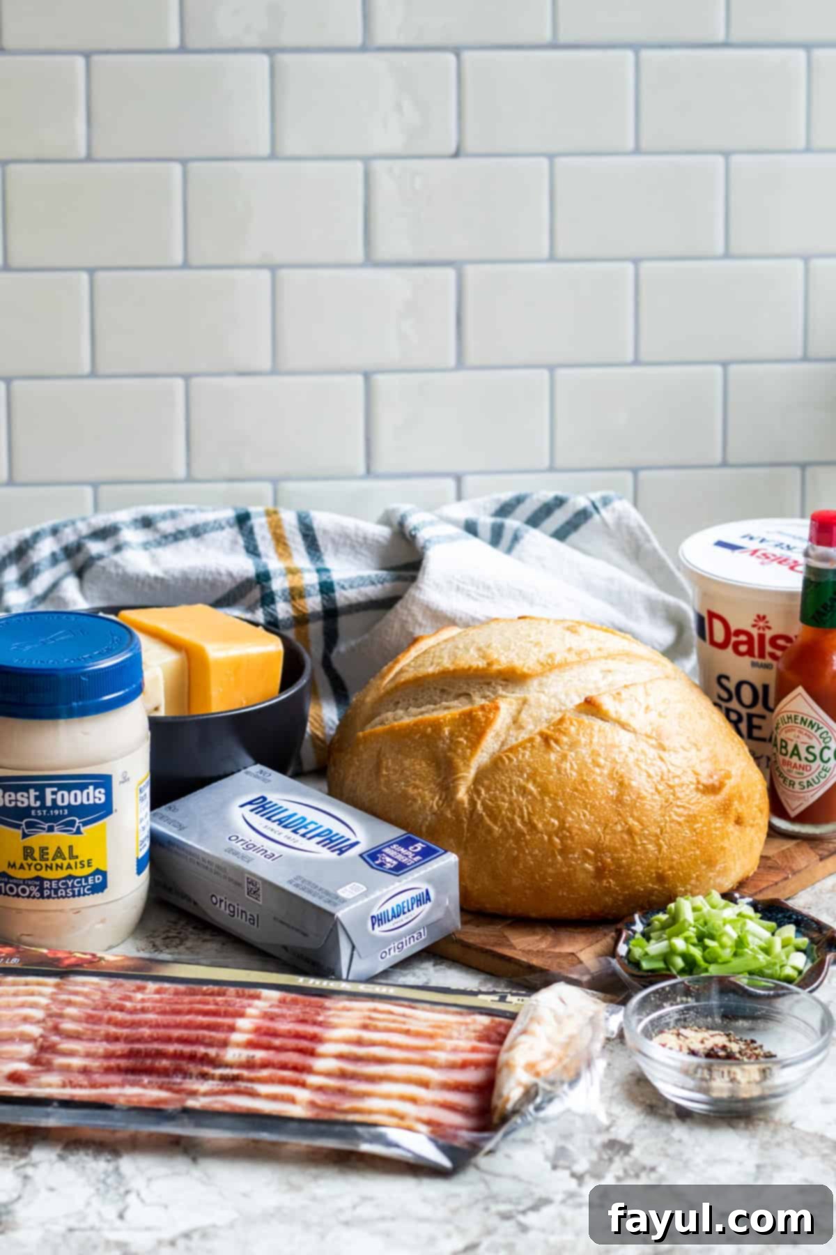 Smoky Bacon Cheese Bread Bowl Fondue 3 Recipe ingredients laid out on counter including various cheeses, bacon, green onions, and condiments.