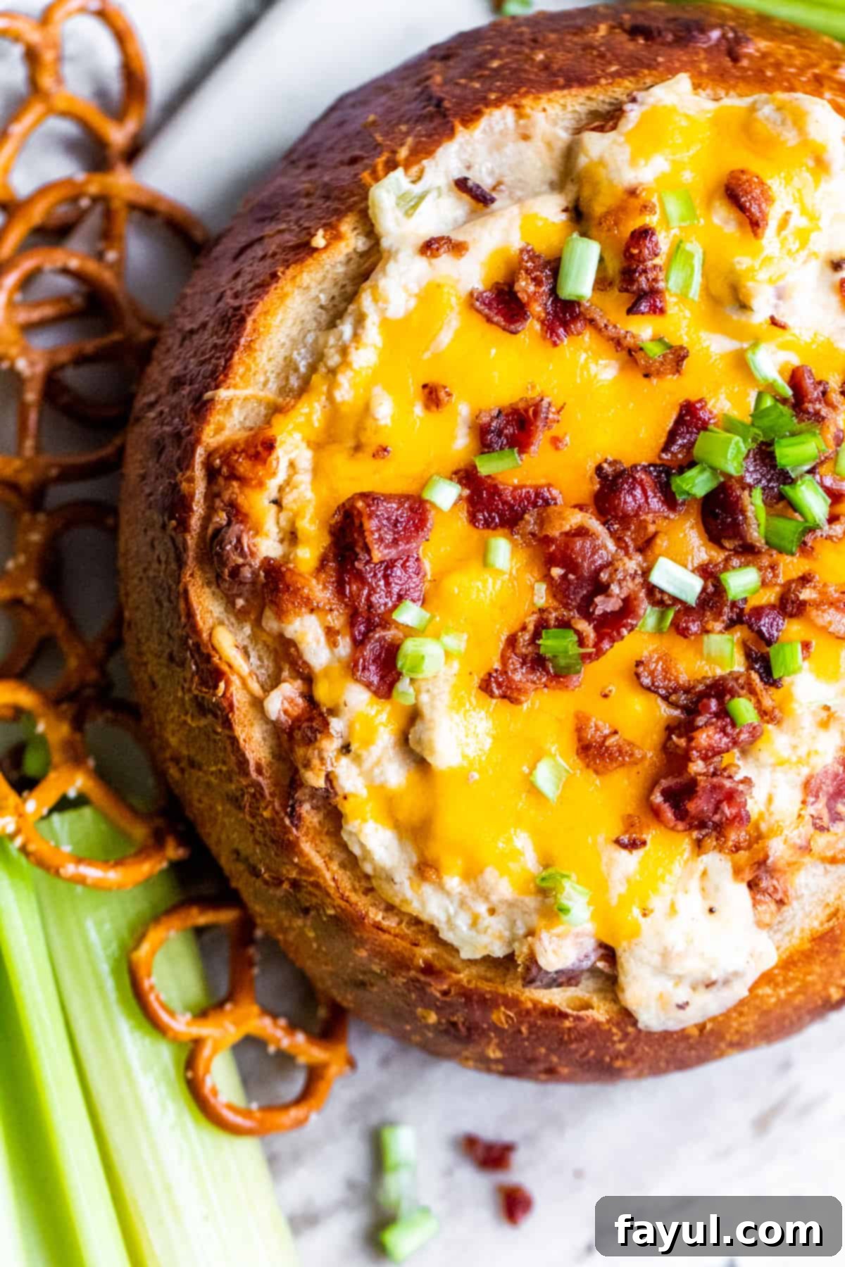 Smoky Bacon Cheese Bread Bowl Fondue 5 Overhead shot of the bacon cheese dip in a bread bowl, surrounded by various dippers like pretzels and celery.