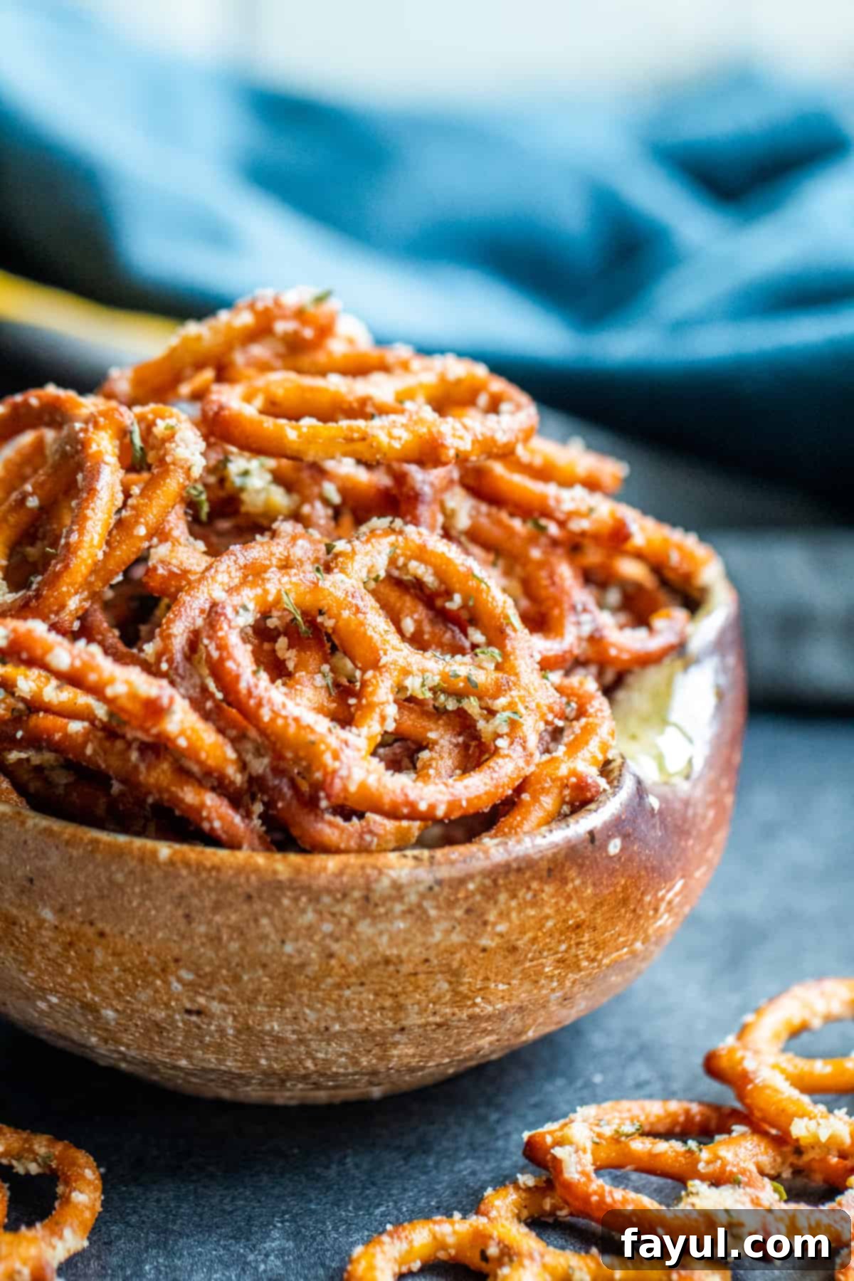 Simple Garlic Parmesan Pretzels 2 A brown bowl overflowing with golden brown garlic parmesan pretzels, ready for snacking.