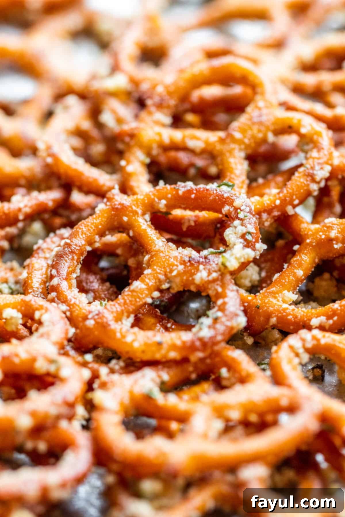 Simple Garlic Parmesan Pretzels 5 Close-up shot of garlic parmesan pretzels scattered on a parchment-lined cookie sheet.