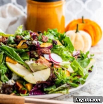 A beautifully composed Fall Harvest Salad on a white plate, with the rich, creamy dressing in a small bowl blurred in the background, ready to be served.
