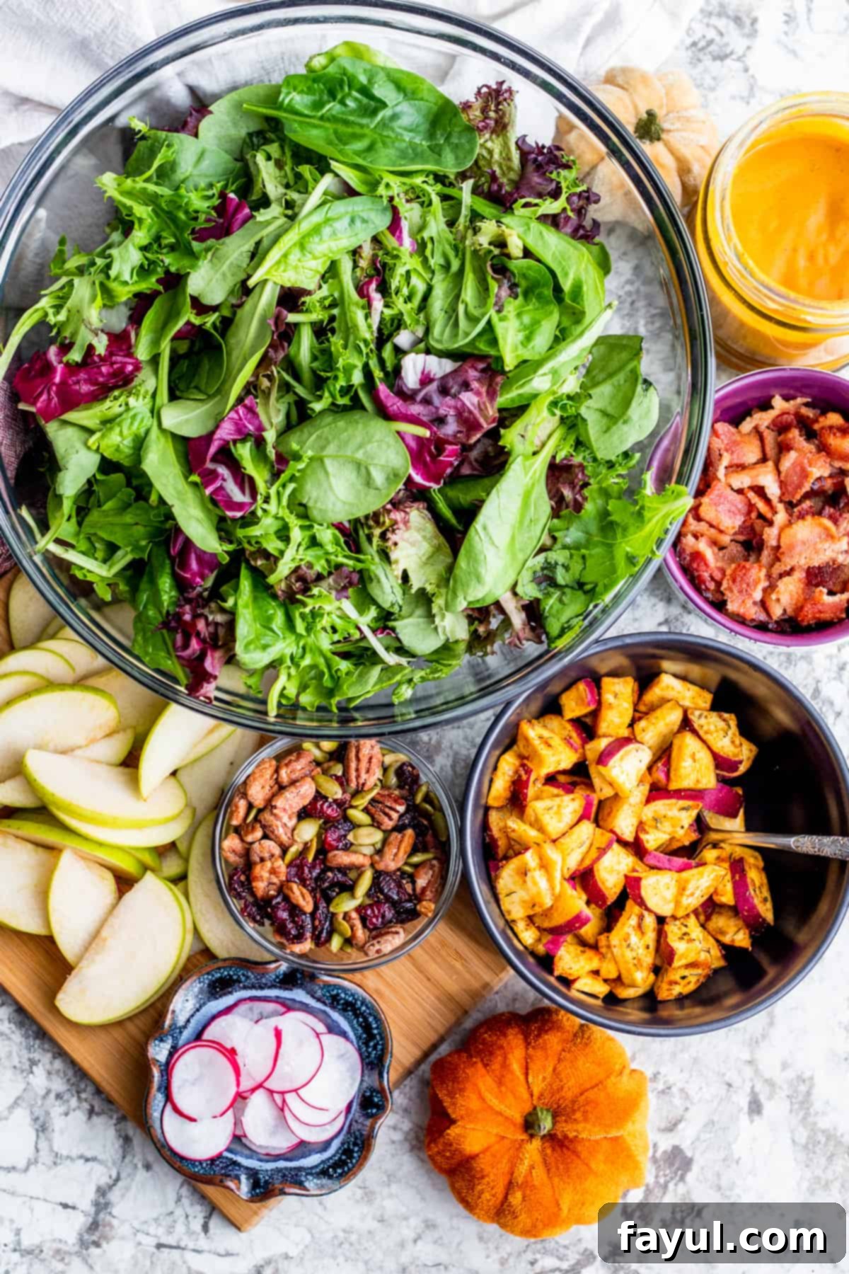 Various fresh ingredients for the Fall Harvest Salad, including chopped sweet potato, fresh greens, sliced apples, and cranberries, neatly arranged in small white bowls on a pristine white kitchen counter, highlighting the quality and freshness.