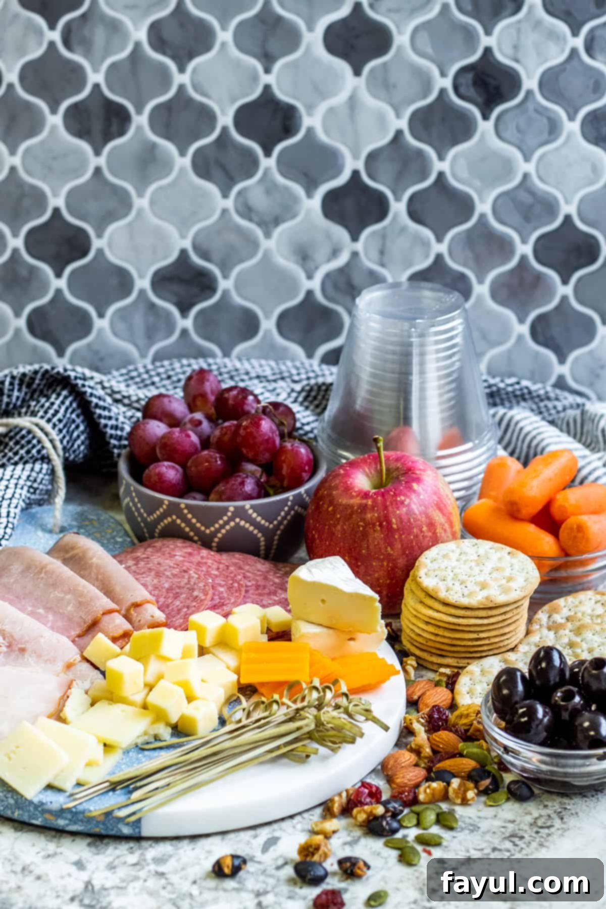 Ingredients for charcuterie laid out on white counter.