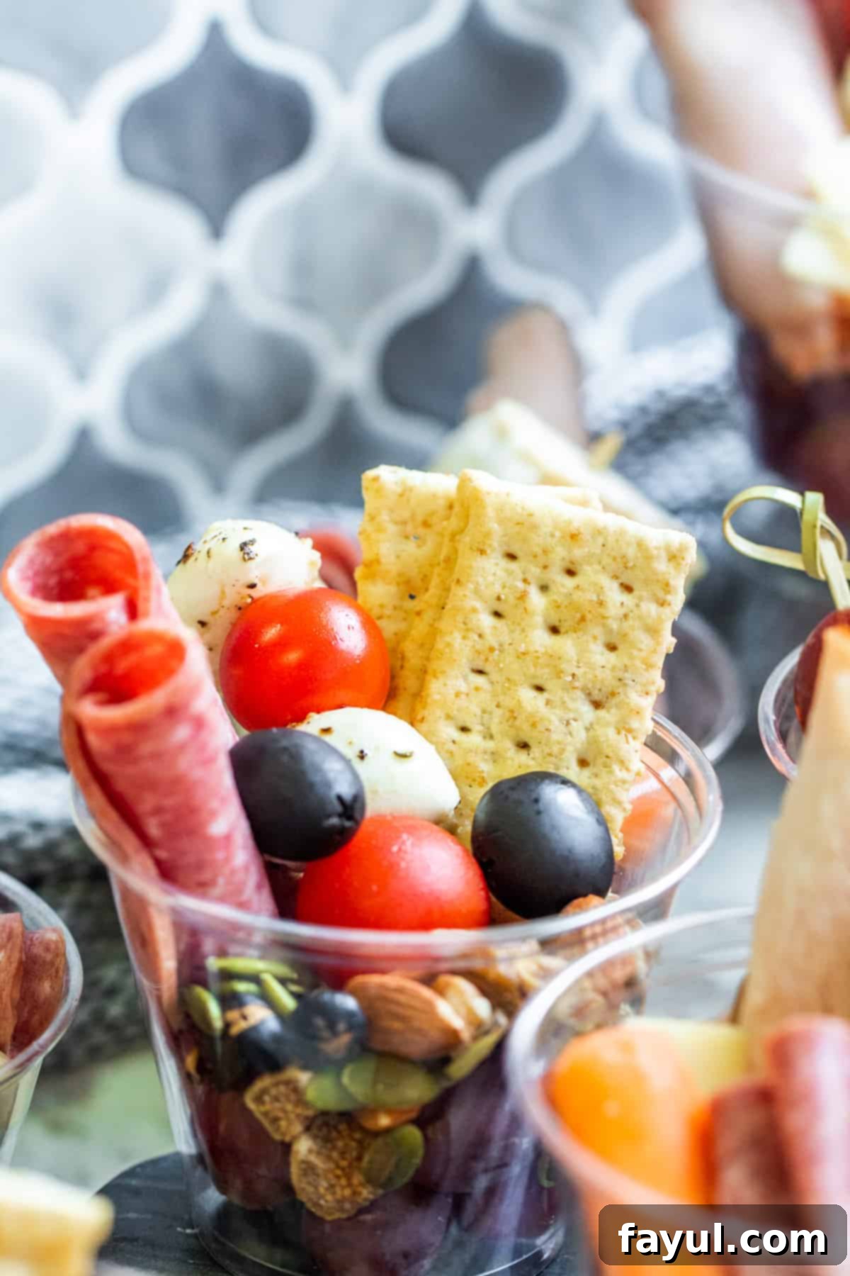 Close up shot of cup with crackers, meat and cheese inside.