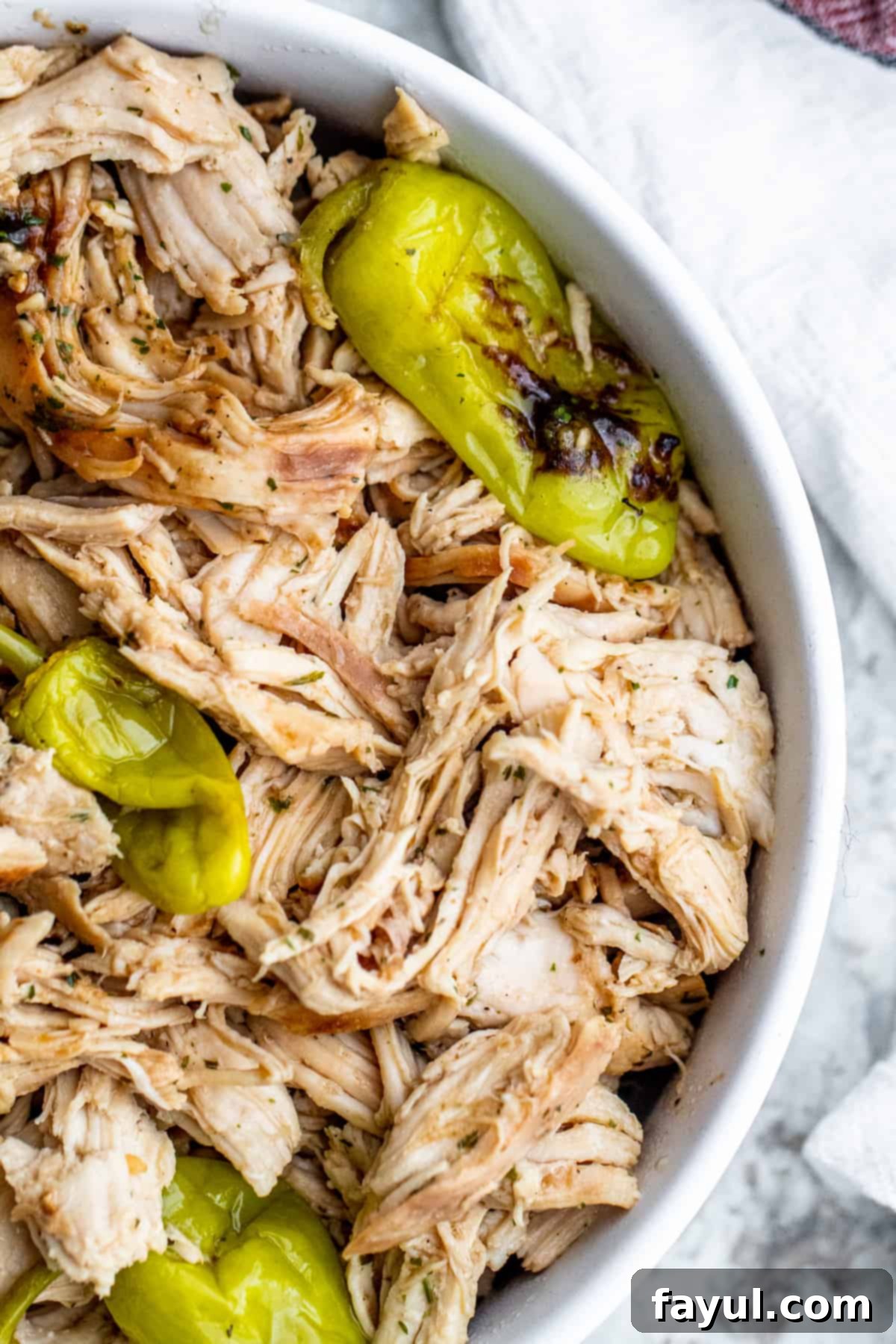 Overhead shot of cooked crockpot chicken in a large white bowl shredded, ready to be served.