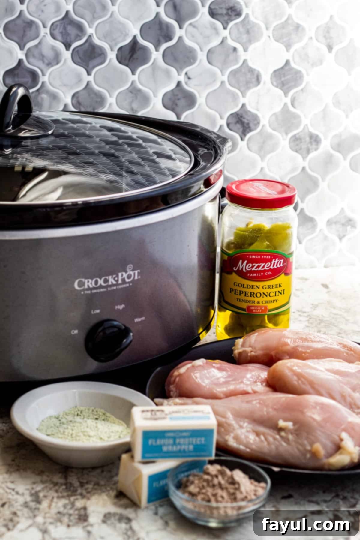 Ingredients for Mississippi Chicken and a crockpot laid out on a white counter on plates and bowls.