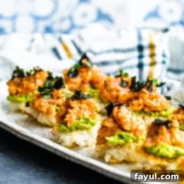 A close-up of a plate featuring several pieces of homemade Spicy Tuna Crispy Rice Sushi on a blue kitchen counter, ready to be enjoyed.