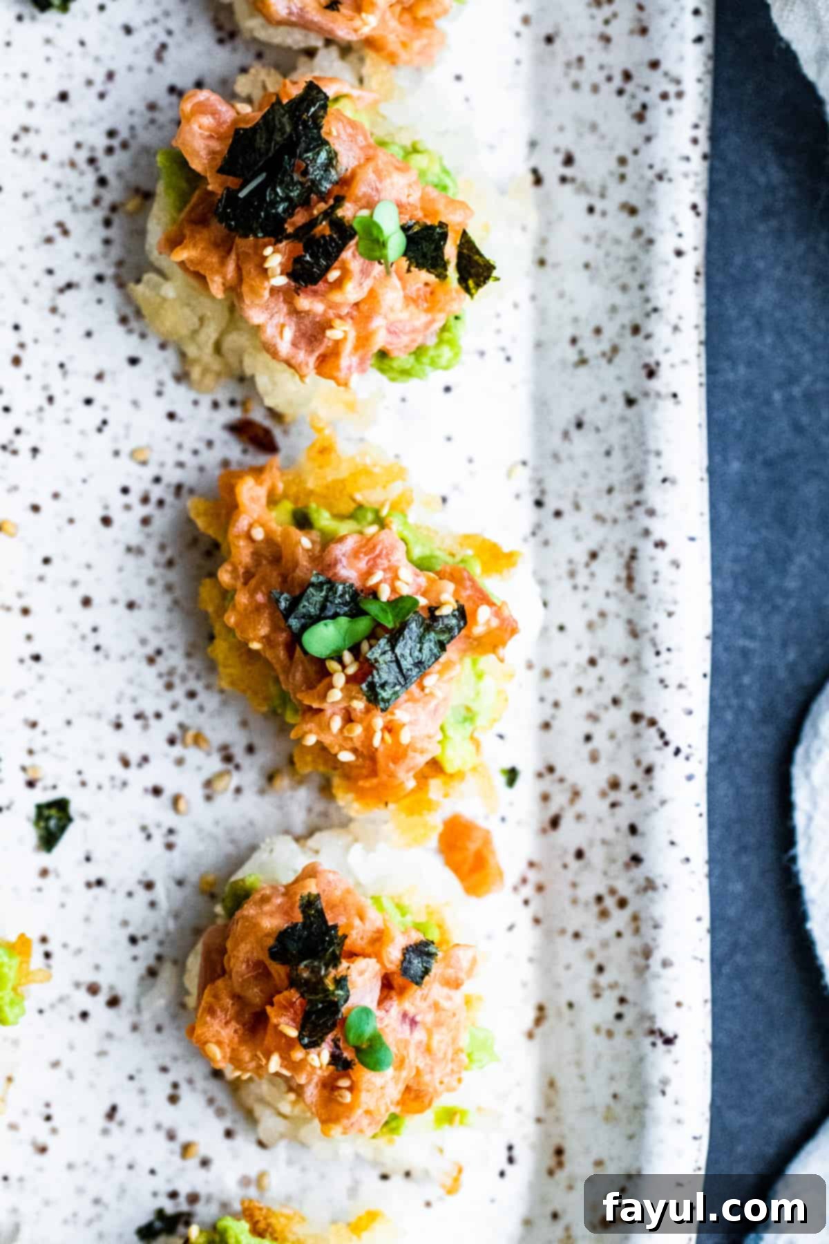 An elegant overhead shot of a white serving plate featuring beautifully arranged Spicy Tuna Crispy Rice Sushi, artfully garnished and ready to be enjoyed.