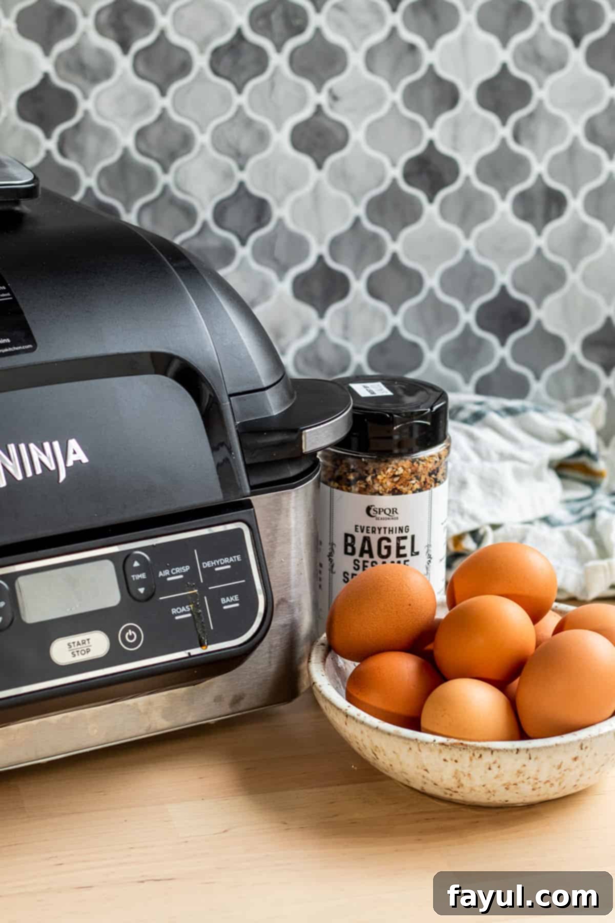 Recipe ingredients in large bowl and air fryer on wooden counter.
