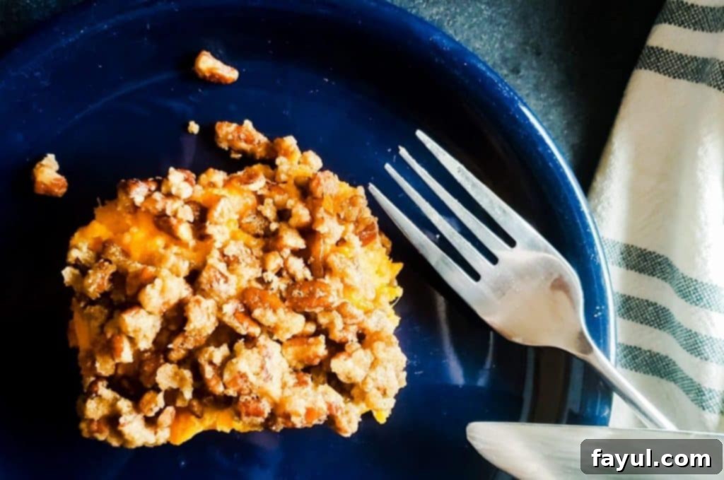 Southern Pecan-Crusted Sweet Potato Delight 3 A single, perfectly portioned piece of Southern Sweet Potato Casserole, showcasing its creamy interior and crunchy pecan topping, served on a delicate blue plate, ready to be enjoyed.
