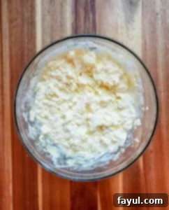 Cream cheese, butter, egg, and vanilla extract being beaten together in a bowl.