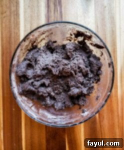 Chocolate cake mix being stirred into the wet ingredients to form the cookie dough.