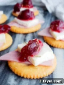Cracker Bites on a blue marble counter, showing several assembled Ritz crackers with ham, brie, and cranberry sauce.