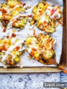 Golden-brown crispy buffalo smashed potatoes on a parchment-lined baking sheet, with a gold spatula lifting one, showcasing melted cheese and sauce.