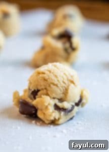 Close-up shot of raw salted chocolate chip cookie dough on a baking sheet, with the perfect texture and visible dark chocolate chips, ready to go into the oven.
