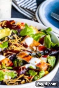 Smoky BBQ Chicken Salad with Creamy Buttermilk Ranch 4 A beautifully presented BBQ Chicken Salad in a white bowl, with a serving plate and the buttermilk ranch dressing visible in the background, ready for a delightful meal.