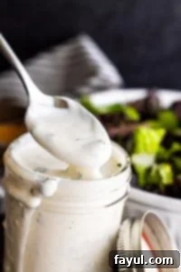 Silver spoon dipping into mason jar filled with ranch.