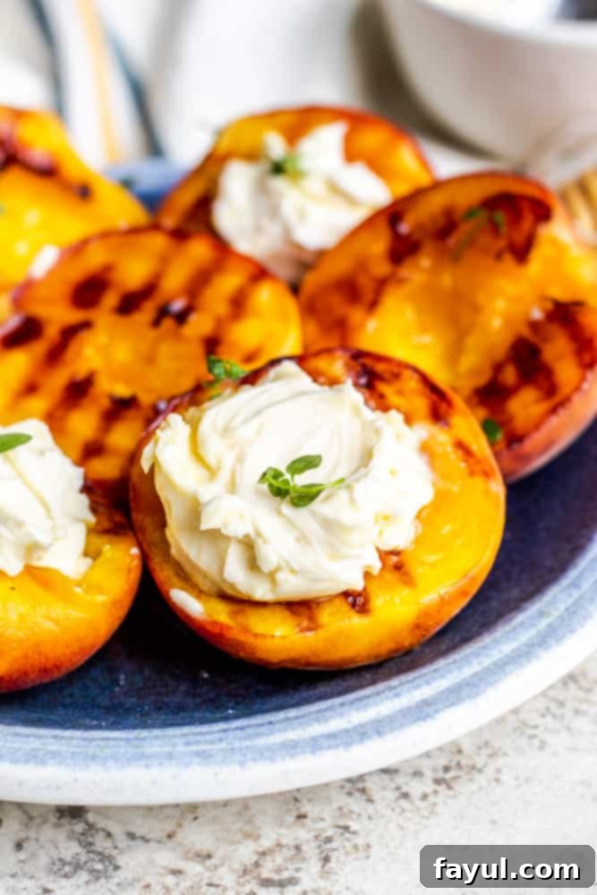 Close up of grilled peaches on a blue plate with mascarpone cheese and thyme on top.