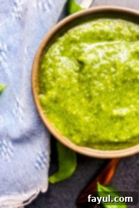 Overhead close up shot of pesto in a gray bowl with a blue napkin next to it.