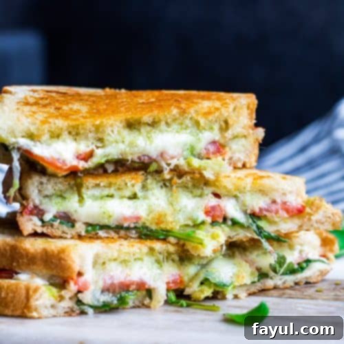 Gourmet Goat Cheese Panini with Arugula Pesto 3 Goat cheese sandwich on a white cutting board, garnished with fresh herbs.