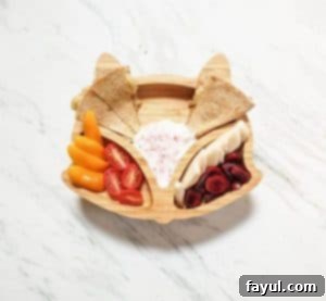 This is a photo of a fox kids plate. The plate containts cherries, yogurt, a quesadilla, pear and tomatoes.