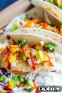 Close-up of a delectable fish taco on a warm tortilla, generously topped with vibrant mango avocado salsa, highlighting the crispy baked coconut-crusted fish.