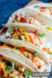 A beautiful shot of several healthy fish tacos arranged on a serving tray, resting on a striking blue countertop, ready to be enjoyed.