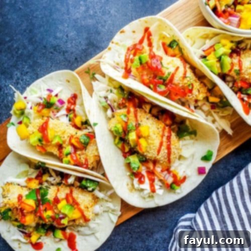 These Baked Coconut Crusted Healthy Fish Tacos with Mango Avocado Salsa is the best, easy recipe for a quick under 30 minute family weeknight dinner! The cod is baked in the oven until crispy, then paired with cilantro lime cabbage slaw for the perfect finish. {VIDEO} #fish #food #healthy #bakedfish #tacos