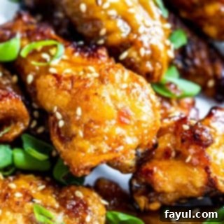 Close up shot of several crispy sweet chili chicken wings garnished with sesame seeds.