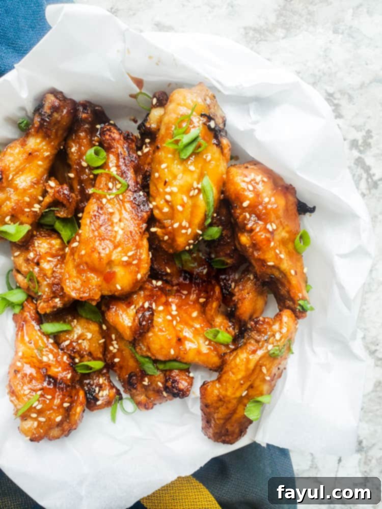 Overhead shot of seasoned chicken wings ready for the air fryer, laid in a bowl with parchment paper.