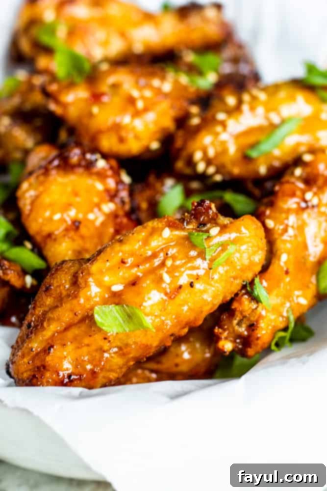 Crispy chicken wings artfully arranged in a parchment paper-lined white bowl, ready for sauce.
