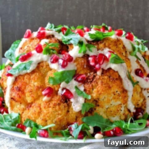 A stunning whole roasted cauliflower drizzled with creamy tahini sauce, presented as an elegant and simple main dish.