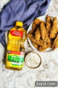 Golden-brown pistachio-crusted chicken tenders neatly arranged on a white plate, ready to be served. A purple napkin adds a touch of color to the background.