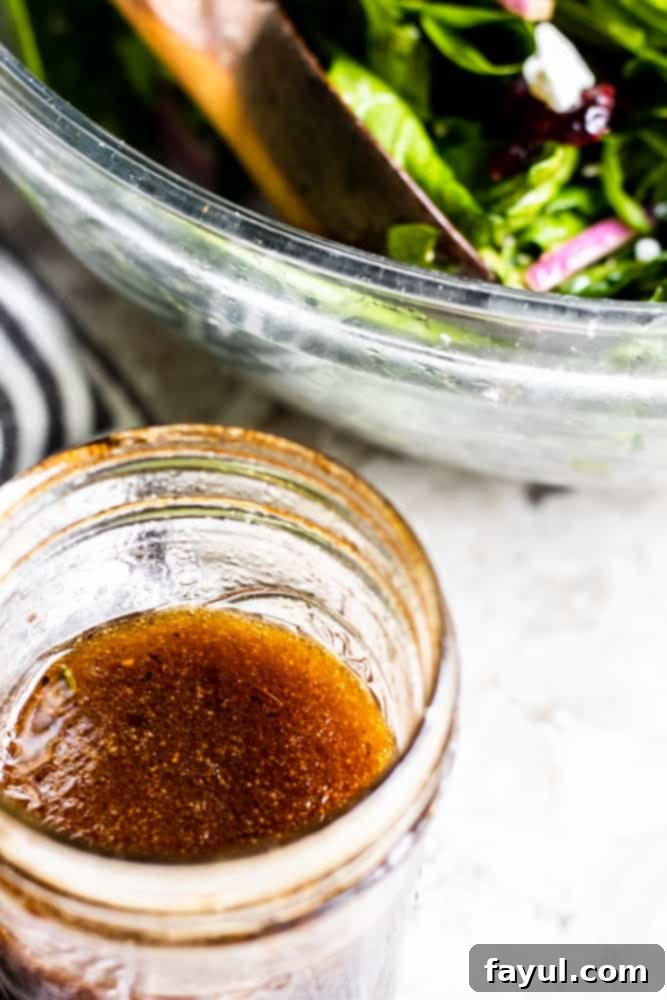 This Homemade Balsamic Vinaigrette Dressing goes great with salads, wraps or as a marinade for meats. This easy and healthy dressing is ready in only 5 minutes and requires no cooking! You will love this light dressing packed with honey, olive oil, balsamic vinegar, garlic and spices. {VIDEO}. #dressing #healthy #vegetarian #glutenfree Balsamic Honey dressing in a glass mason jar sitting on a white counter.