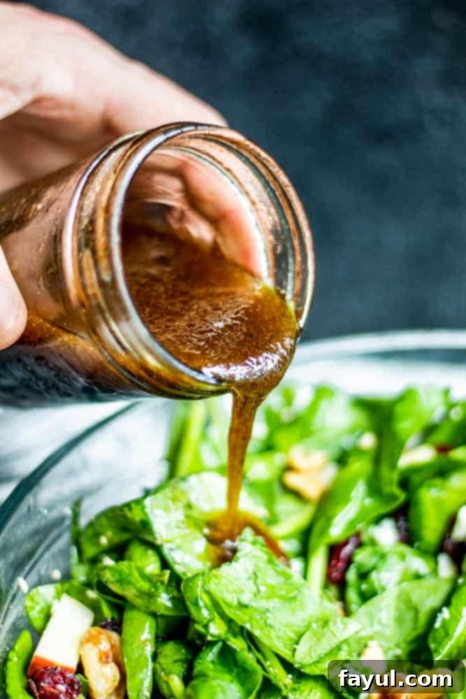 This Homemade Balsamic Vinaigrette Dressing goes great with salads, wraps or as a marinade for meats. This easy and healthy dressing is ready in only 5 minutes and requires no cooking! You will love this light dressing packed with honey, olive oil, balsamic vinegar, garlic and spices. {VIDEO}. #dressing #healthy #vegetarian #glutenfree #recipe #easyrecipe #food Homemade Balsamic Dressing being poured over salad in a glass bowl.