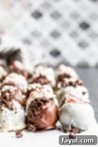 Strait on shot of Oreo truffle balls on parchment paper in three lines on a blue counter.