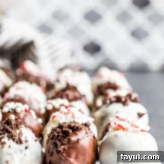 Strait on shot of Oreo truffle balls on parchment paper in three lines on a blue counter.
