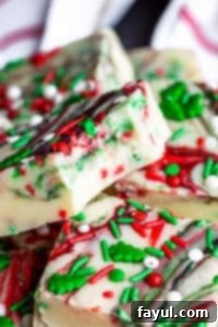 Homemade Sugar Cookie Fudge: Simple, Festive, and Perfect for Christmas Gifting with Rubbermaid TakeAlongs Sugar cookie fudge stacked on top of each other with a bite taken out of the top piece, showcasing festive sprinkles and a smooth texture.