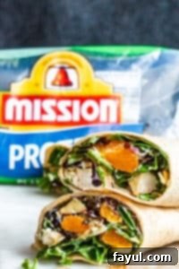 Two healthy chicken wraps stacked on top of each other on a blue background.