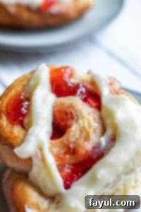 Close up of the swirled top of a strawberry roll, showing the fruit filling and golden-brown crust.