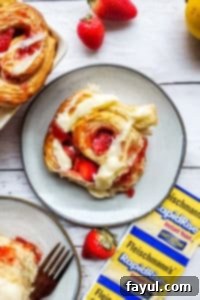Overhead shot of a single strawberry roll on a grey plate, placed on a clean white counter.