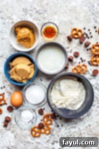 Individual ingredients for peanut butter cup cookies displayed in separate glass bowls on a white kitchen counter, awaiting mixing.