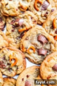 Peanut butter pretzel cookies stacked neatly on top of each other on white parchment paper, ready to be enjoyed.