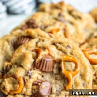 Peanut butter cup cookies arranged in a row on top of each other on white parchment paper, ready to be served.