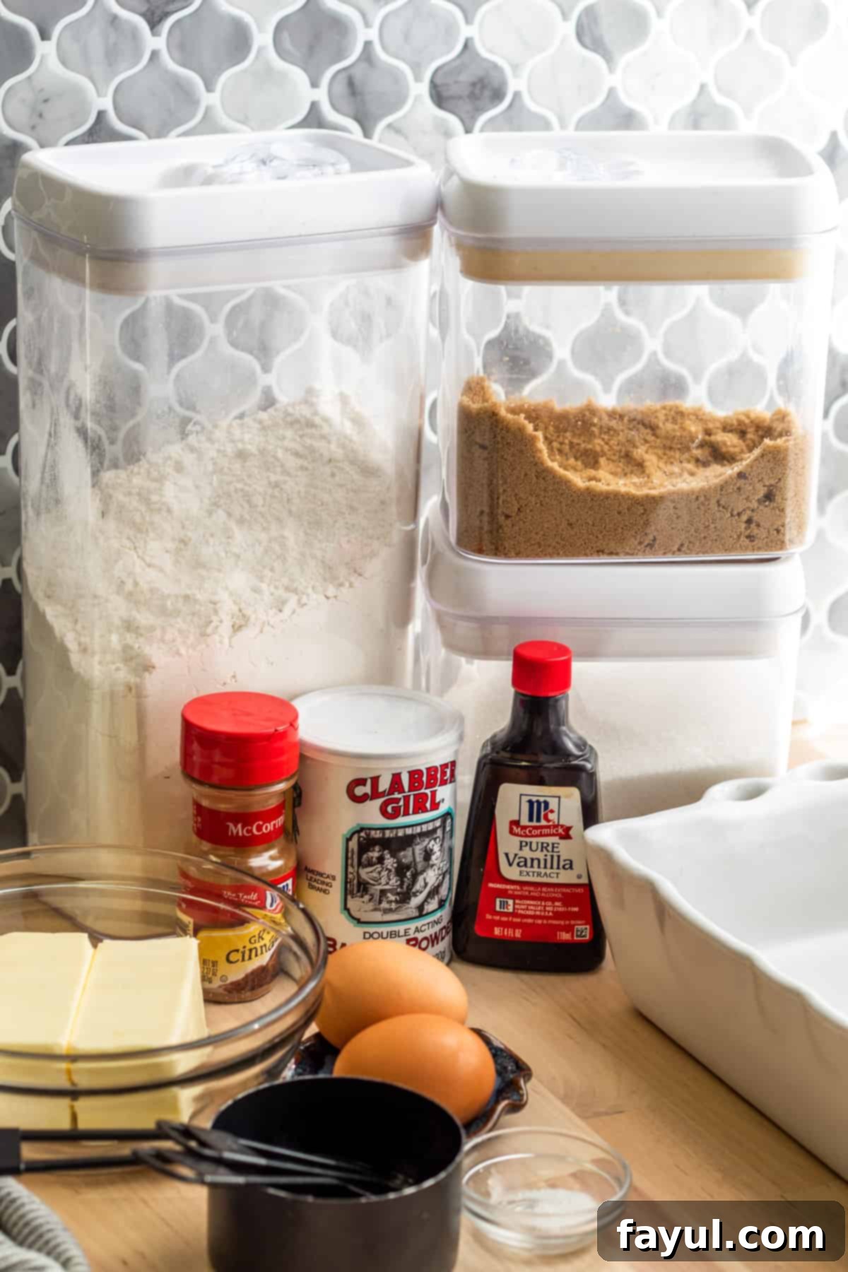 Various ingredients for snickerdoodle blondies laid out on a white surface, including butter, sugars, flour, and spices, ready for preparation.