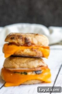 Make Ahead Breakfast Sandwiches: Stacked and ready for quick, delicious meal prep. Freezer-friendly and customizable for busy mornings. Two perfectly stacked make-ahead breakfast sandwiches on a white counter, ready to be enjoyed.