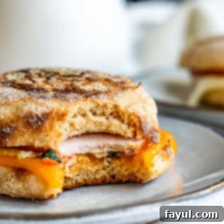 Freezer-Ready Breakfast Sandwiches 3 A delicious make-ahead breakfast sandwich on a gray plate with a bite taken out, resting on a white kitchen counter.