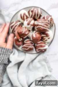 Enjoying the Finished Raspberry Truffles: A Perfect Sweet Moment Beautifully arranged raspberry truffles on a stylish gray plate, set on a white marble counter, with a hand gently reaching for one.