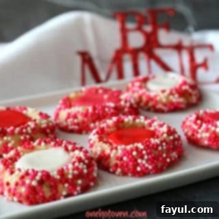 Colorful Valentine's Day thumbprint cookies decorated with red, white, and pink sprinkles, and filled with sweet icing, an ideal treat for a special Valentine.